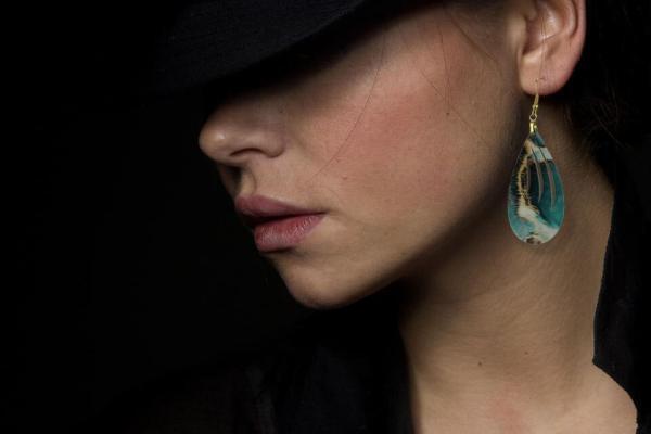 Jade look teardrop earrings on a woman wearing a hat