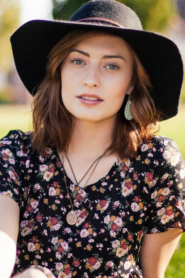 Yellow blossom teardrop earrings on a woman wearing a hat