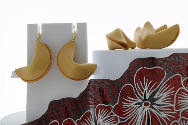 fortune cookie dangle earrings next to loose fortune cookies with an Asian fan in front